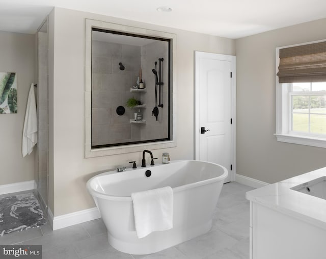 full bathroom with a tile shower, a freestanding bath, baseboards, and a sink