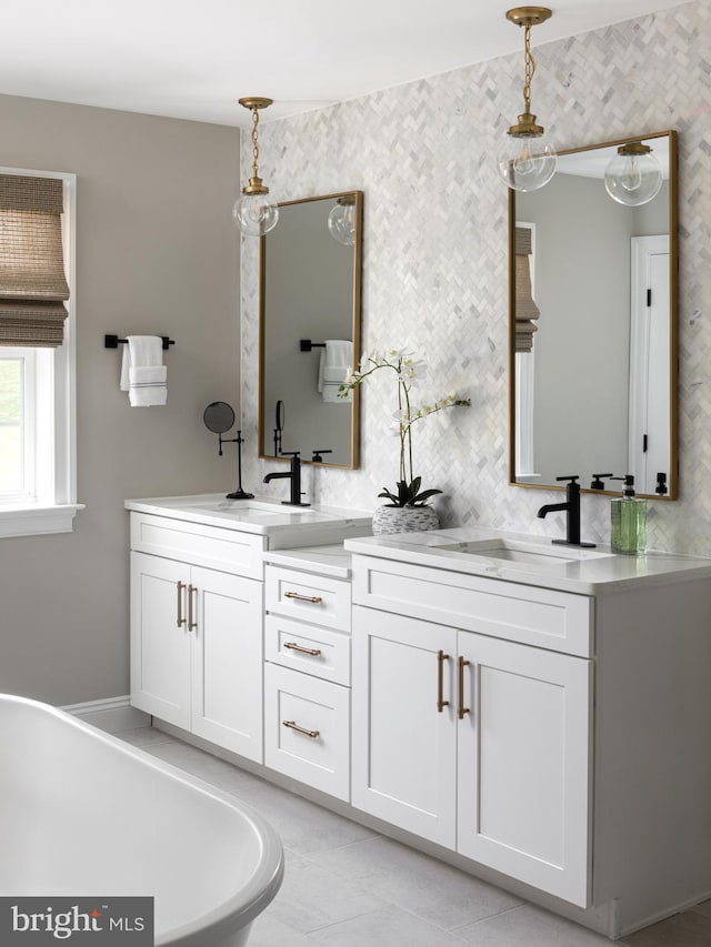bathroom featuring double vanity, a freestanding tub, and a sink