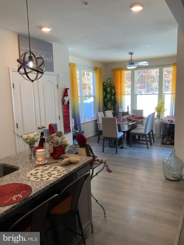 dining area with ceiling fan with notable chandelier and light hardwood / wood-style flooring