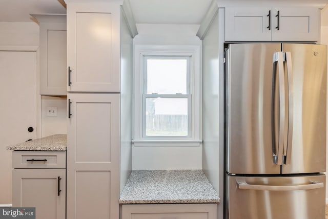 kitchen featuring light stone countertops, white cabinets, and stainless steel refrigerator