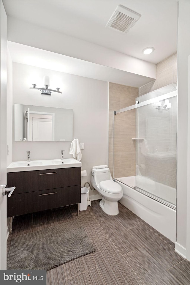 full bathroom featuring tile flooring, toilet, double vanity, and combined bath / shower with glass door