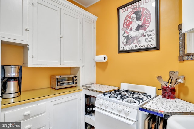 kitchen with white cabinetry, crown molding, and white range with gas stovetop