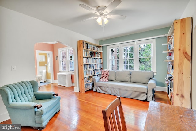 living room with wood-type flooring, ceiling fan, and radiator