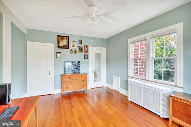 interior space with ceiling fan, radiator, and light wood-type flooring