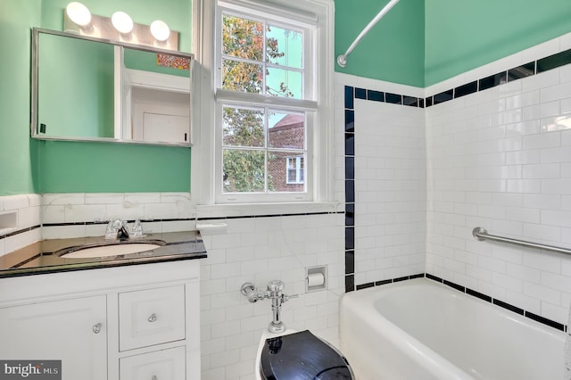 bathroom featuring tile walls, large vanity, and tiled shower / bath