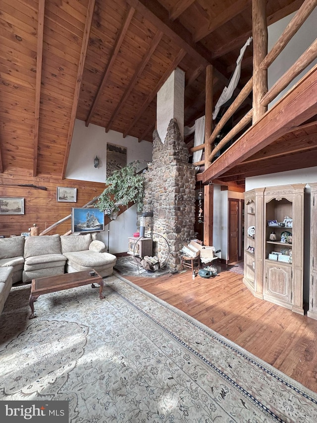 unfurnished living room featuring beam ceiling, wooden walls, wood ceiling, and hardwood / wood-style flooring