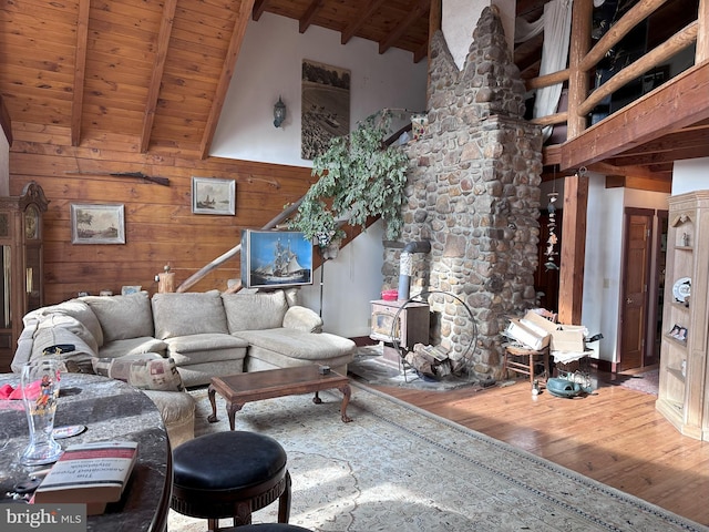 living room with a wood stove, beamed ceiling, high vaulted ceiling, hardwood / wood-style floors, and wooden walls