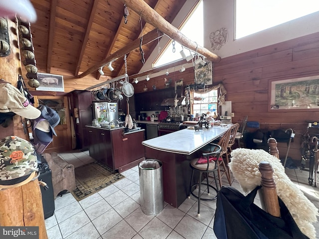 kitchen featuring light tile patterned floors, high vaulted ceiling, and an island with sink