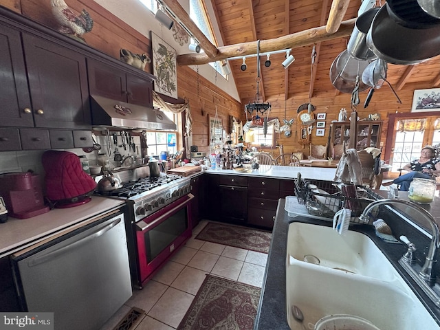 kitchen with wood walls, sink, vaulted ceiling with beams, stainless steel appliances, and extractor fan