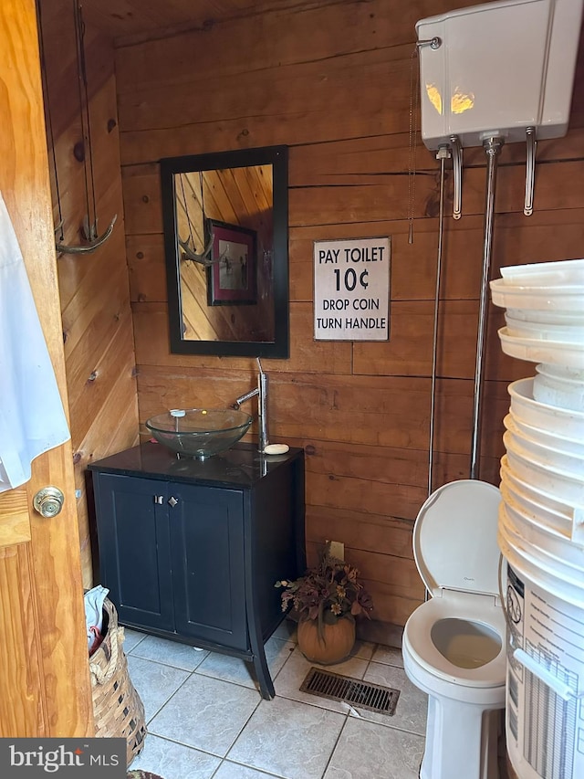 bathroom with toilet, vanity, tile patterned floors, and wood walls