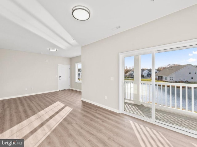 spare room with light wood-type flooring and a water view