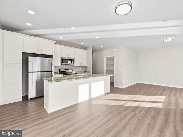 kitchen with a center island with sink, stainless steel appliances, light wood-type flooring, and white cabinetry