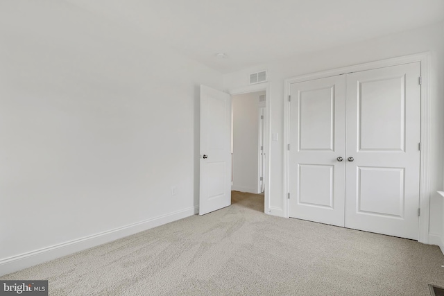 unfurnished bedroom featuring light carpet and a closet