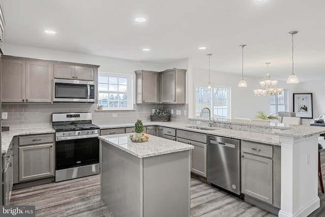 kitchen with a kitchen island, sink, light wood-type flooring, and stainless steel appliances