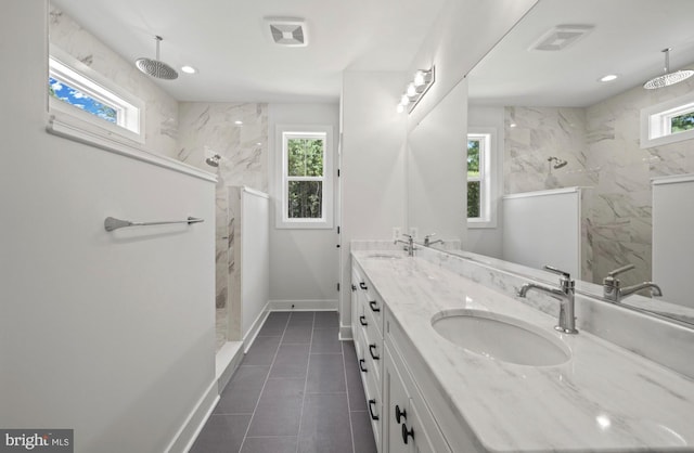 bathroom featuring a tile shower, tile floors, double sink, and large vanity