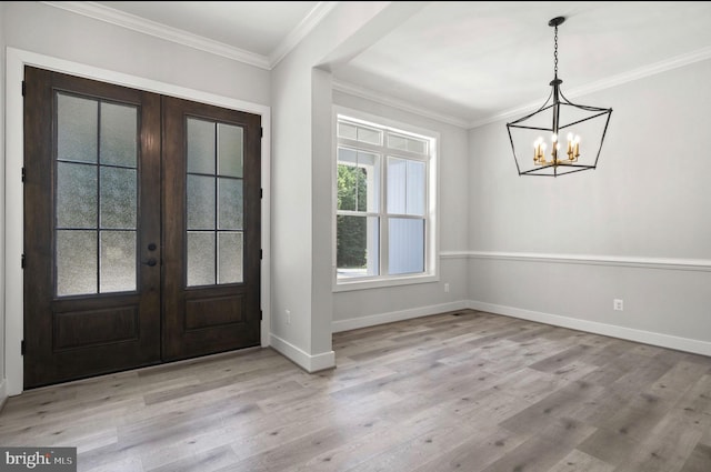 foyer with french doors, ornamental molding, a chandelier, and light hardwood / wood-style floors