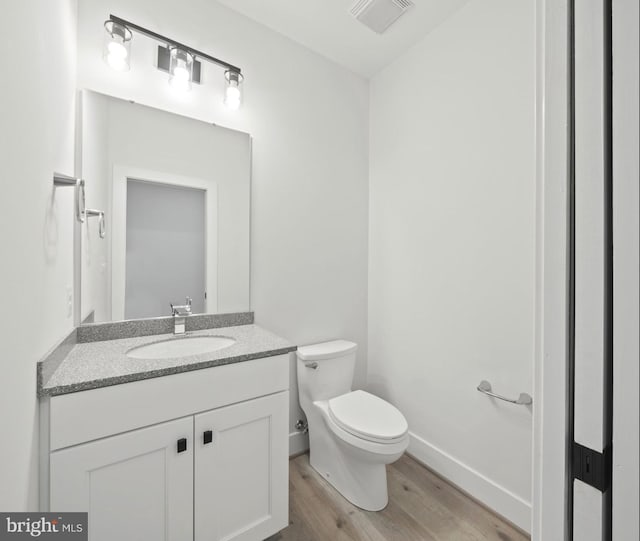 bathroom featuring toilet, hardwood / wood-style floors, and oversized vanity