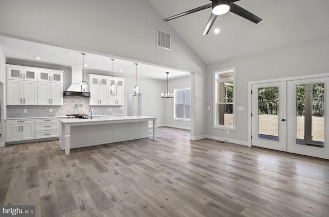 kitchen with pendant lighting, backsplash, ceiling fan with notable chandelier, light hardwood / wood-style flooring, and white cabinets