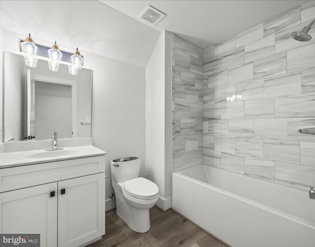 full bathroom with tiled shower / bath combo, toilet, hardwood / wood-style flooring, and vanity with extensive cabinet space