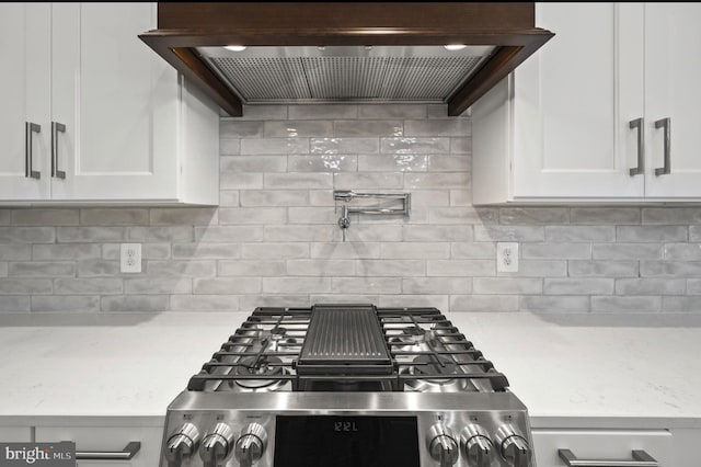 kitchen with range, white cabinetry, custom exhaust hood, light stone counters, and tasteful backsplash