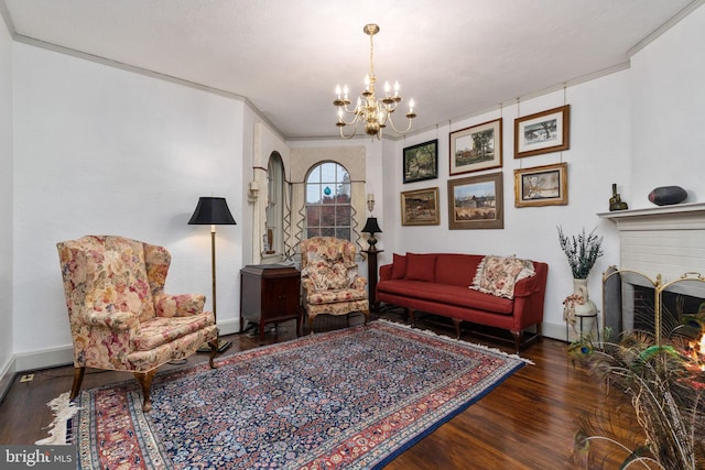 living room with a chandelier, crown molding, a brick fireplace, and dark hardwood / wood-style flooring