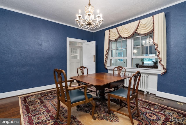 dining area featuring hardwood / wood-style floors, a textured ceiling, a chandelier, and crown molding