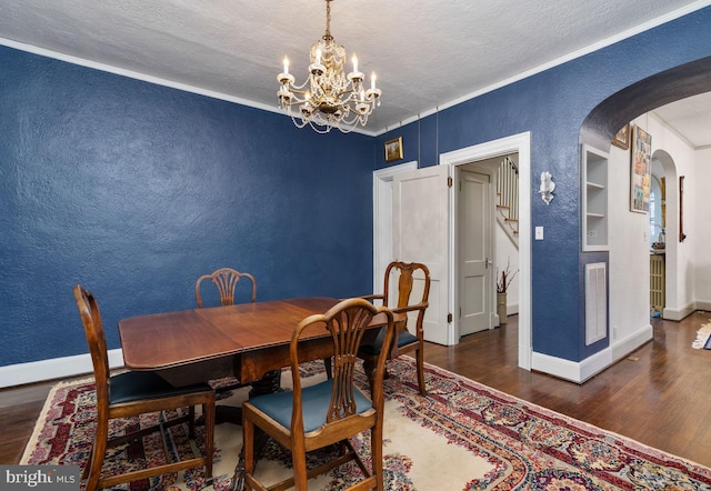 dining space with a textured ceiling, a chandelier, built in shelves, crown molding, and dark hardwood / wood-style flooring