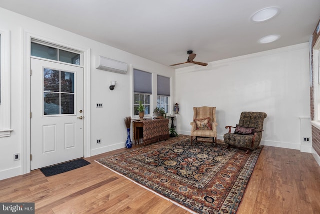 interior space with ceiling fan, a wall unit AC, and hardwood / wood-style floors