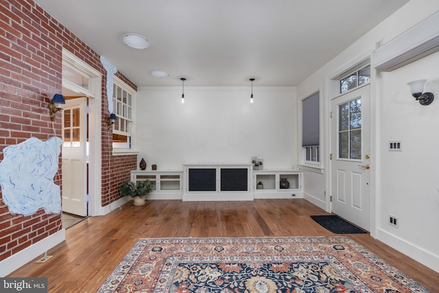 interior space with brick wall, an AC wall unit, and light hardwood / wood-style flooring