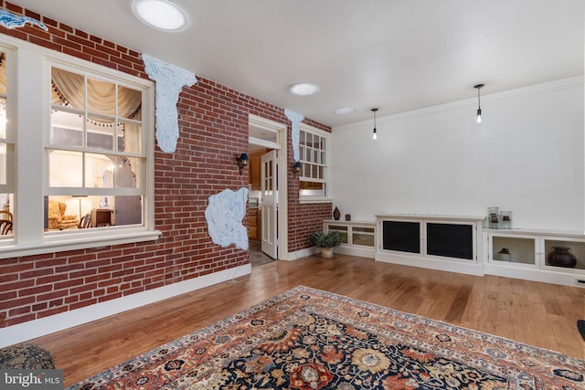 interior space with brick wall, wood-type flooring, and crown molding