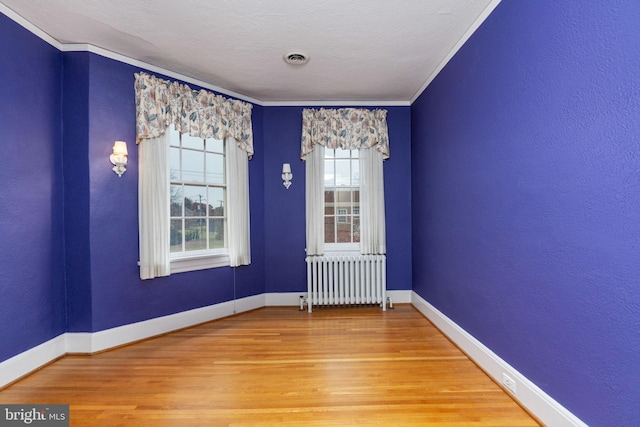 unfurnished room with ornamental molding, light hardwood / wood-style floors, a textured ceiling, and radiator heating unit