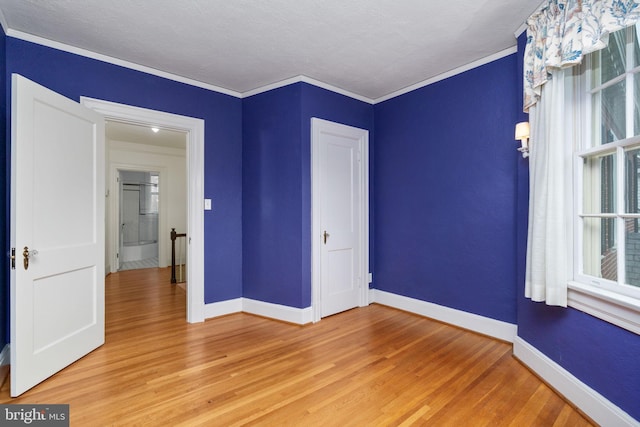 unfurnished room featuring ornamental molding, light hardwood / wood-style flooring, and a textured ceiling