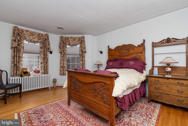 bedroom with radiator heating unit and light wood-type flooring