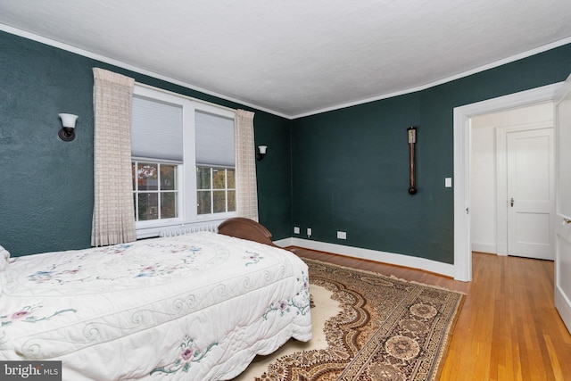 bedroom featuring light hardwood / wood-style flooring, radiator heating unit, and ornamental molding