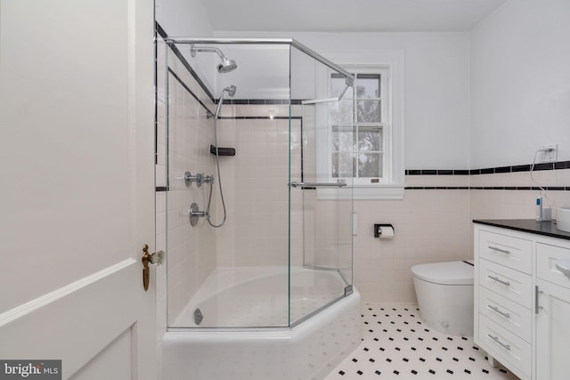 bathroom featuring vanity, tile floors, toilet, and tile walls