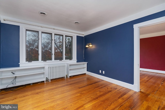 empty room with radiator heating unit and light wood-type flooring