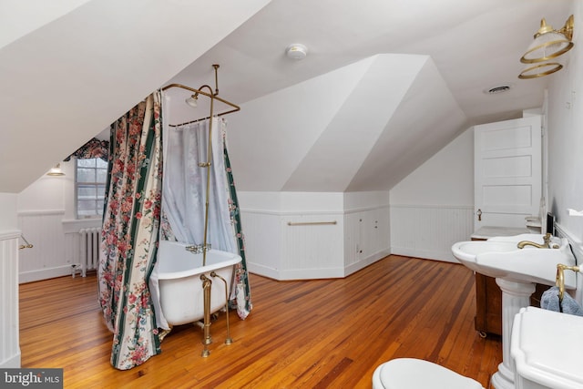 bathroom featuring hardwood / wood-style floors, vaulted ceiling, radiator heating unit, and toilet