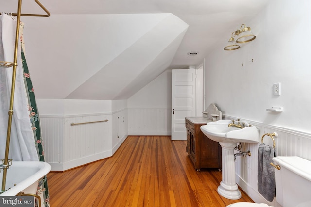 bathroom with hardwood / wood-style floors, vaulted ceiling, and toilet