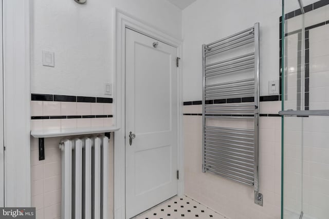 bathroom with tile walls, tile flooring, and radiator