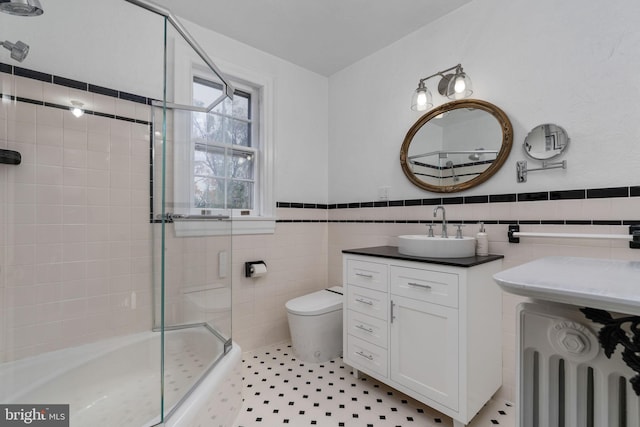 bathroom with tile flooring, tile walls, toilet, vanity, and radiator