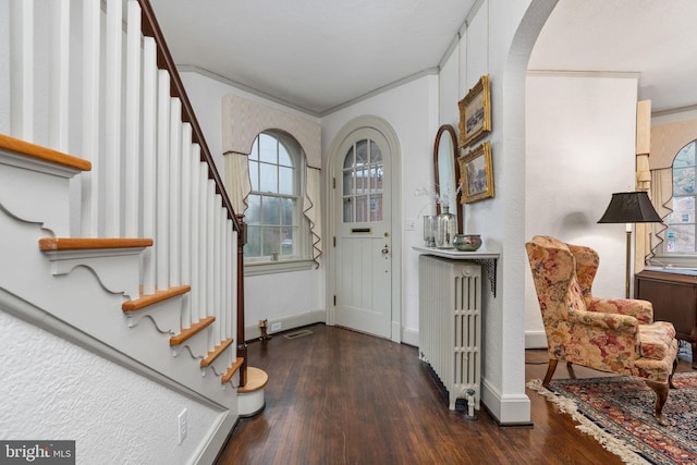 foyer entrance with ornamental molding, dark wood-type flooring, and radiator