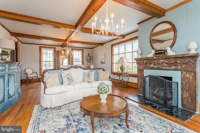 living room featuring hardwood / wood-style floors, a notable chandelier, beam ceiling, and crown molding