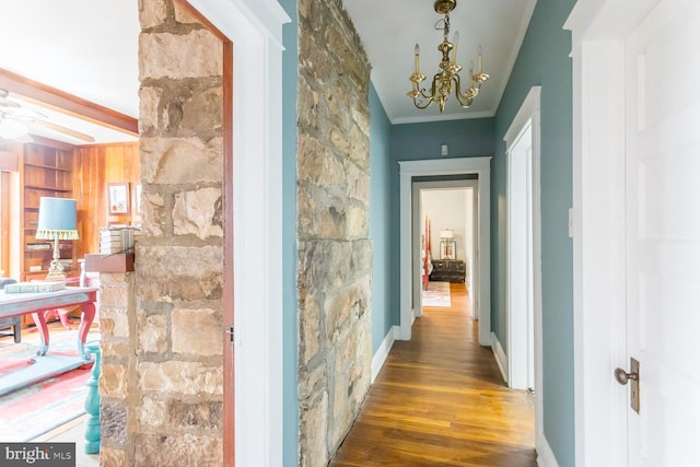 hallway featuring dark hardwood / wood-style floors, ornamental molding, and an inviting chandelier