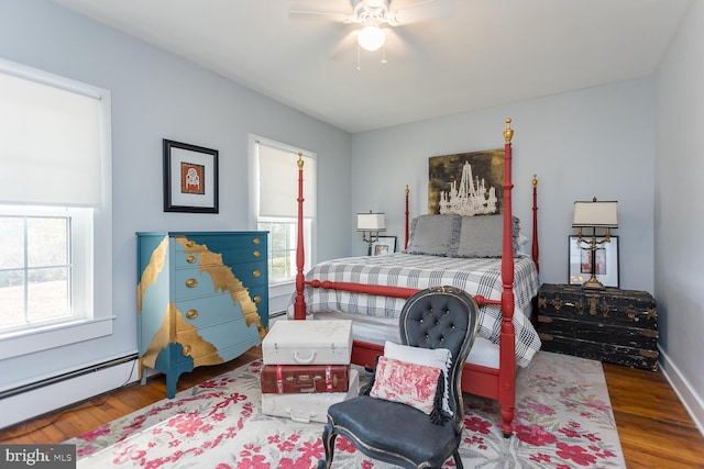 bedroom with ceiling fan, a baseboard heating unit, and hardwood / wood-style flooring