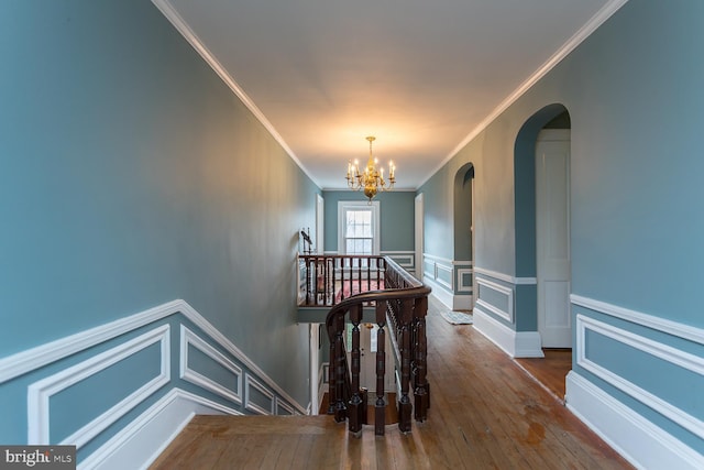 hall featuring hardwood / wood-style flooring, ornamental molding, and a chandelier