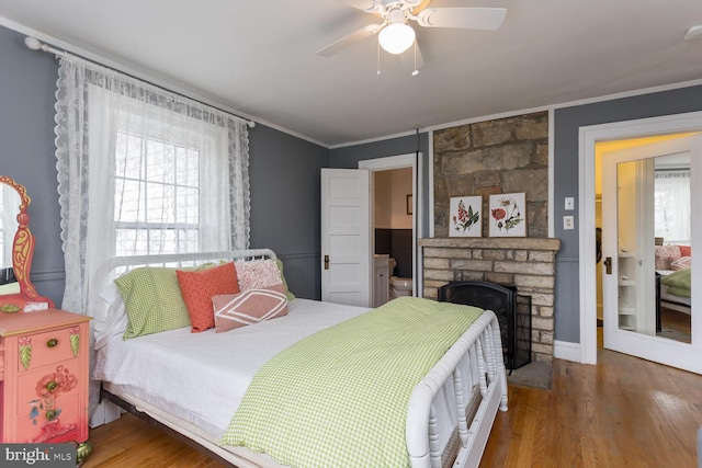 bedroom featuring a fireplace, hardwood / wood-style floors, ceiling fan, and ornamental molding