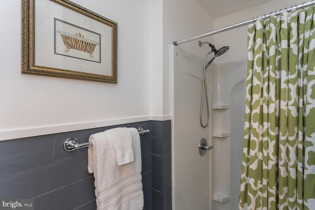 bathroom with curtained shower and tile walls