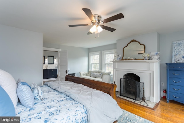 bedroom with light wood-type flooring, ensuite bathroom, and ceiling fan