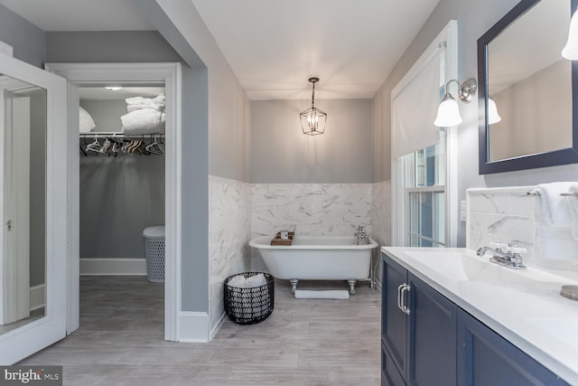 bathroom with vanity, a tub, and tile walls