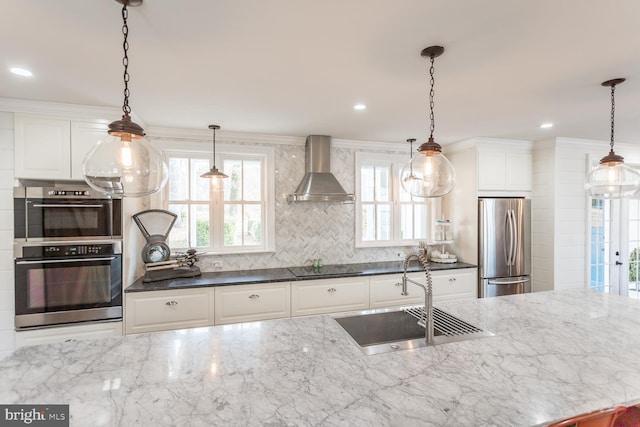 kitchen featuring dark stone counters, sink, wall chimney exhaust hood, white cabinetry, and stainless steel appliances